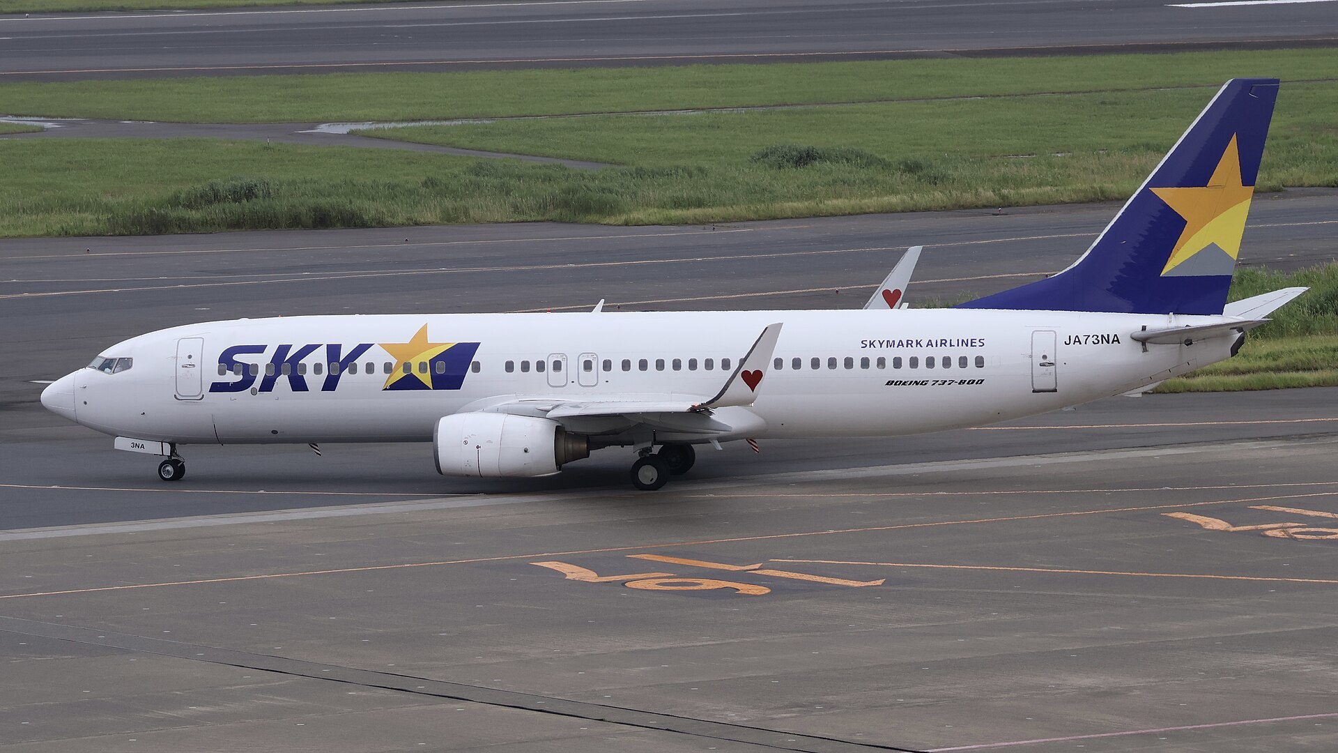Skymark 客機喺跑道準備起飛,雲層之上,遠處係日本城市景觀