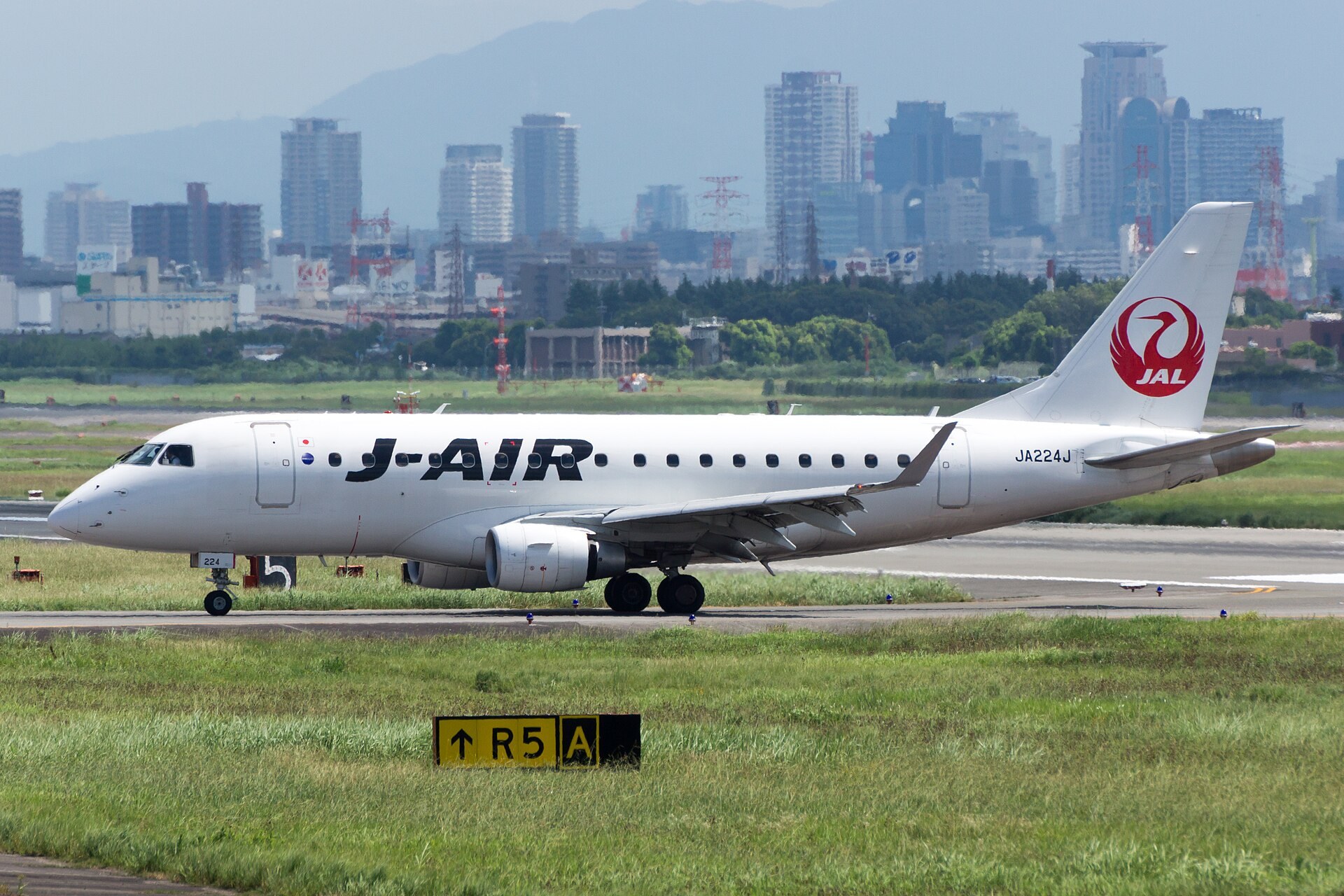 J-AIR 客機停泊喺機場,旁邊立住一個 Jibungurumi 玩偶