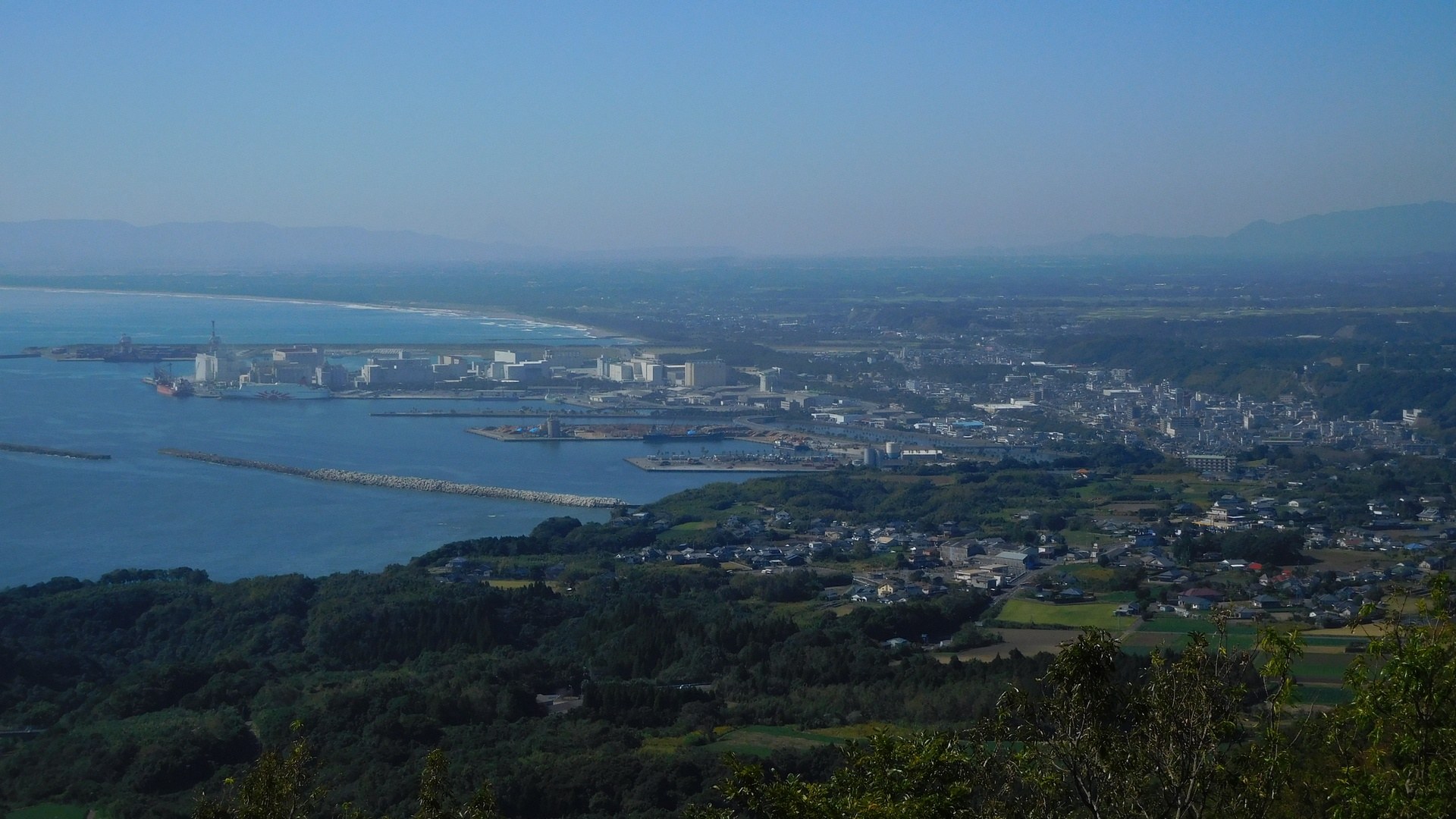 渡輪停靠港口，遠處山脈同城市建築，海邊天晴