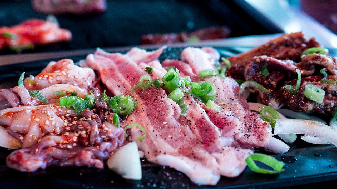韓式燒肉料理拼盤同冷麵擺喺木桌上，寫實新聞攝影風格