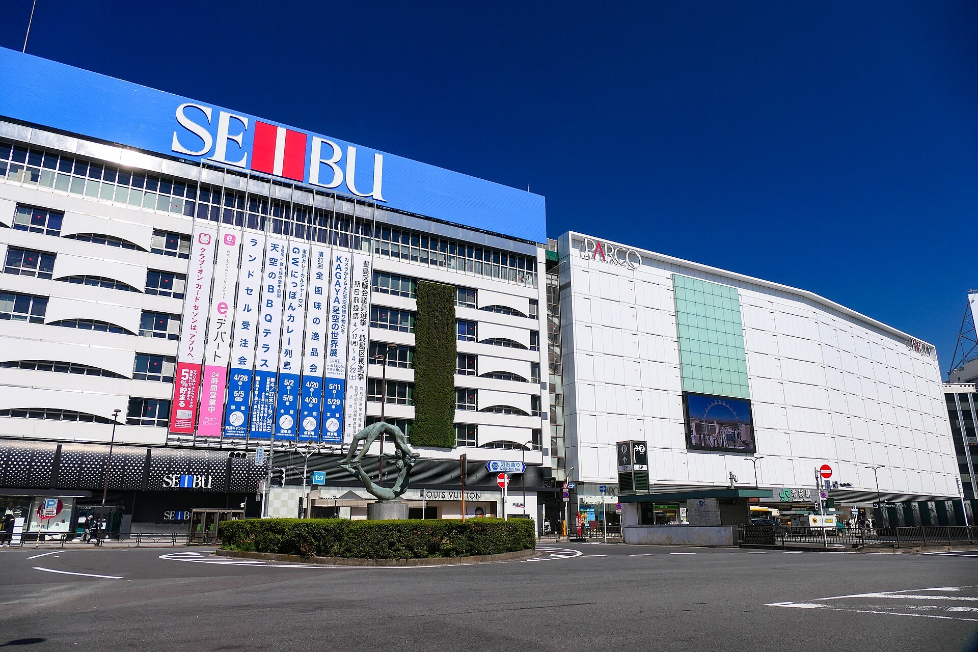 池袋「ダイヤゲート池袋」2樓線路上空公開空地「ダイヤデッキ」嘅夜空市集：暖色燈飾嘅餐飲攤檔、天文望遠鏡星空觀望，背景係鐵軌。