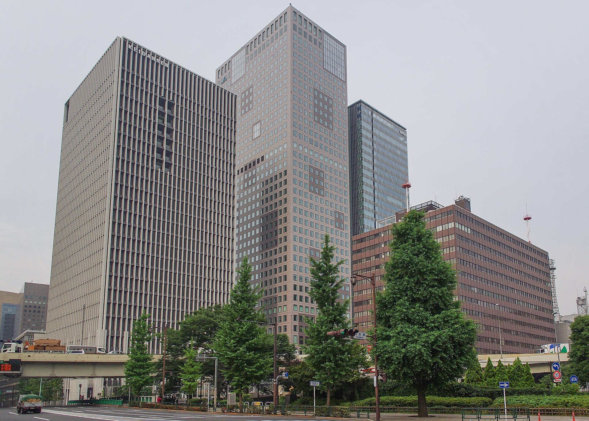 東京大丸有街區建築外牆嘅城市藝術展示場景，行人經過