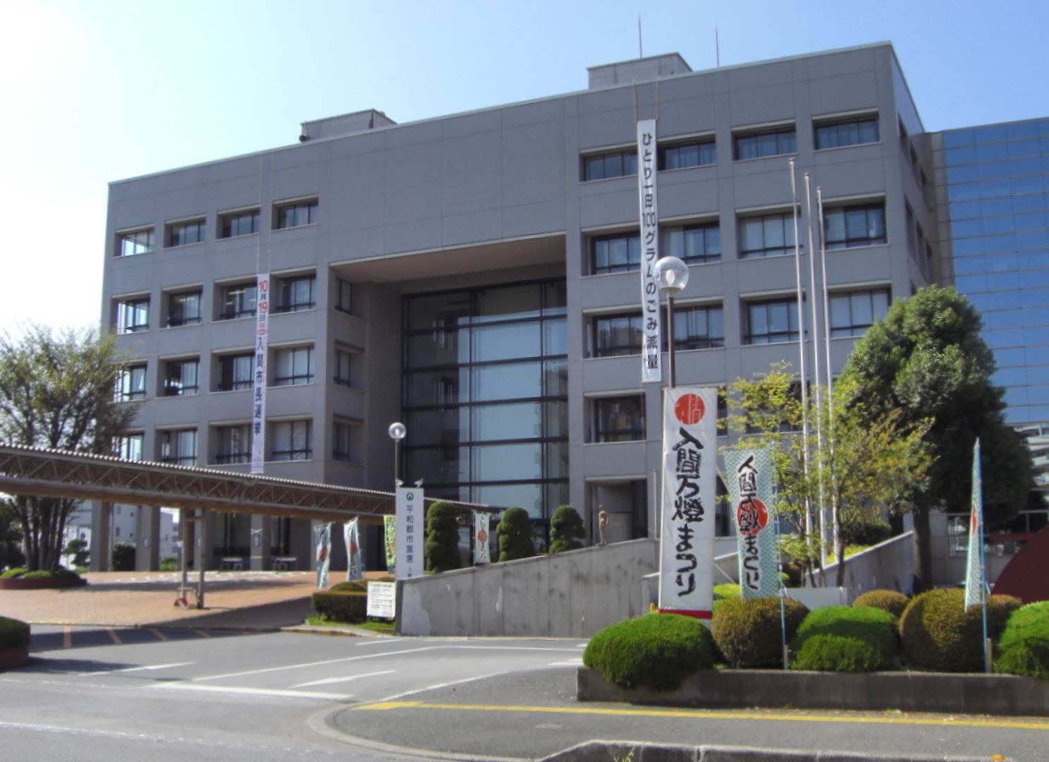 動漫聯名設計嘅井盖，背景為帶紅色锯齿狀屋頂嘅文化設施（示意圖）