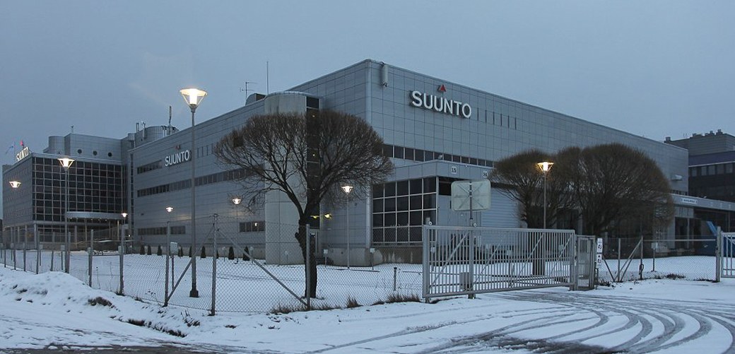 放置喺岩石上的 Suunto Core 2 戶外運動鐘錶，背景係山徑同樹林