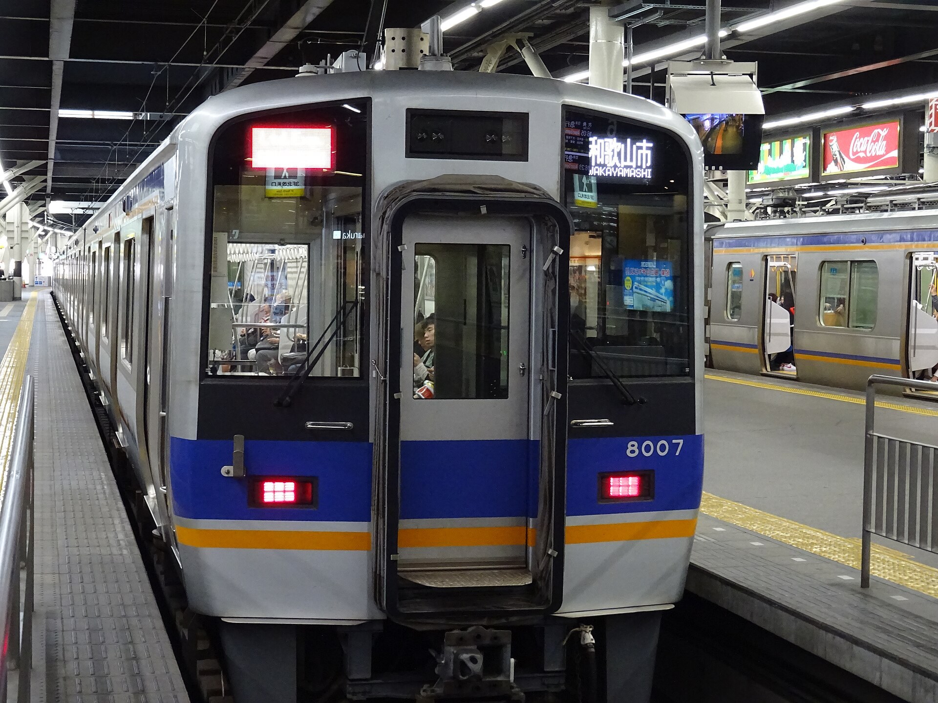 大阪難波廣場夜晚，廣場佈滿高懸嘅燈籠同巨型眼球造型藝術裝置，遊人喺裝置之間穿過，背景係難波都市天際線。