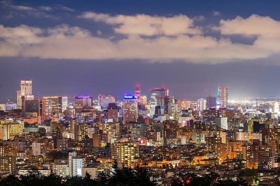 夜空中綻放嘅冬季花火,背景係大雪覆蓋嘅跳台競技場剪影,遠處人群靜立觀看,faces not visible。