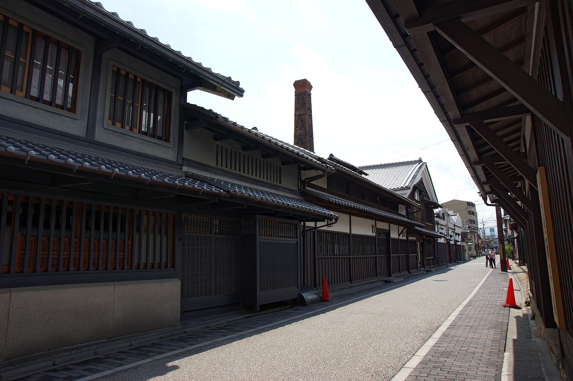 日本酒蔵木造建築,屋頂積著薄霜,門前擺滿木製酒樽
