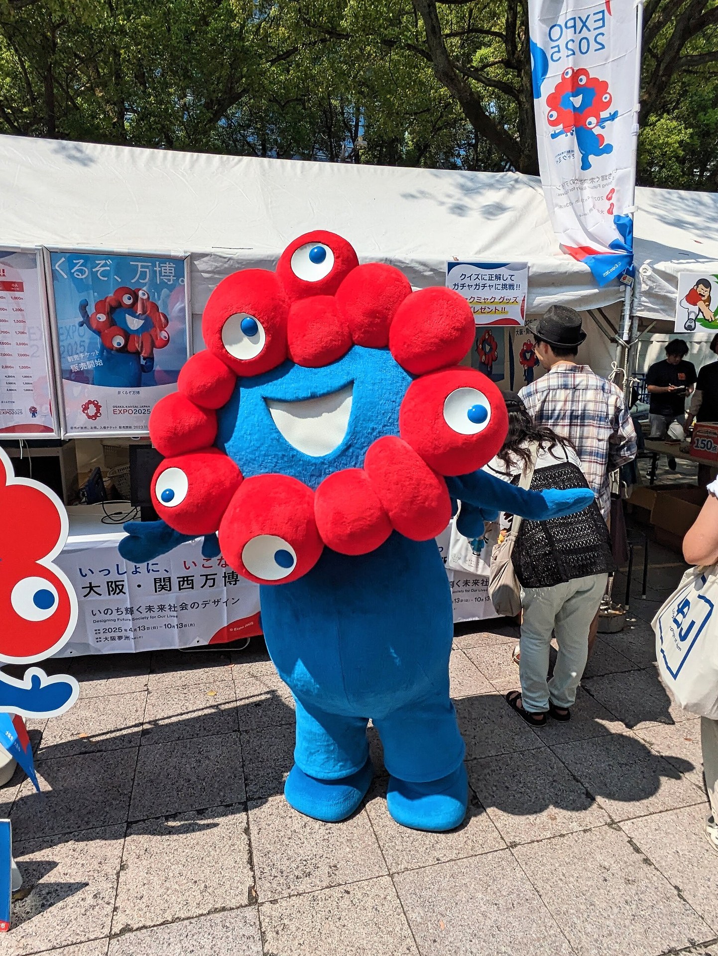 身穿書店圍裙嘅卡通大眼吉祥物公仔，米色同綠色配色